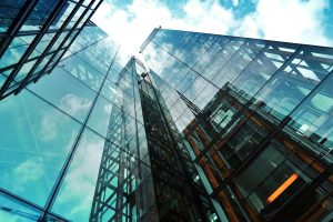 A striking view of a modern glass skyscraper reflecting the sky and clouds.